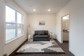 Located at 1547 Pacific Avenue in Santa Cruz, California, this efficiently designed single-floor unit offers a well-organized layout comprising a kitchen, living room, and full bathroom. The kitchen is a standout feature, outfitted with stainless steel appliances including a refrigerator, range, microwave, and dishwasher, complemented by white cabinetry, dark stone-style countertops, and warm wood-tone flooring. Recessed lighting keeps the space bright and functional. The living area benefits from a large window that frames views of surrounding greenery, filling the room with natural light and creating a calm, inviting atmosphere. A glass-paned door opens to a private balcony, extending the living space outdoors and enhancing the connection to the outdoors. The bathroom is clean and contemporary, featuring a single-sink vanity with matching dark countertop, a large mirror, and a full tub-shower combination. Wood-look flooring runs consistently throughout the unit, tying the spaces together with a cohesive, modern aesthetic. Crisp white walls and a neutral color palette give the unit a bright, airy feel. The unit's location in downtown Santa Cruz places it within close proximity to local shops, dining, and the Pacific coastline.