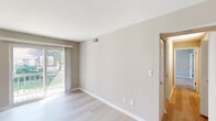 This single-floor residence at 172 S Budding Ave in Virginia Beach, VA offers a well-organized layout designed for comfortable living. The main living area features light-toned luxury vinyl plank flooring and neutral wall tones, creating a bright, airy atmosphere. A sliding glass door opens directly to a private balcony overlooking green surroundings, while an additional window allows natural light to fill the space from multiple angles. The open flow connects the living area to an adjacent dining or secondary living space, both finished with the same cohesive flooring.

The kitchen is appointed with crisp white shaker cabinetry, sparkling quartz countertops, a tile backsplash, a stainless steel undermount sink, and a stainless steel dishwasher, combining style with practicality. Bedrooms are carpeted for comfort; one features a window with outdoor views and dual bifold closets providing generous storage, while the primary bedroom includes a walk-in closet and private en-suite bathroom. The en-suite is equipped with a vanity, toilet, and additional storage. Throughout the unit, consistent neutral tones, white trim, and thoughtful storage solutions contribute to a clean, modern aesthetic.
