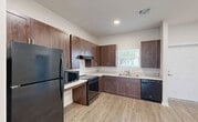 This 880 square foot apartment in Florida City, FL offers a contemporary living space with two bedrooms and two bathrooms. The single-story layout maximizes efficiency, with the primary bedroom measuring a comfortable 170 square feet. The heart of the home is an open-concept living area that seamlessly integrates the kitchen and living room. The kitchen boasts rich, dark wood cabinetry, contrasting beautifully with light countertops and modern black appliances. Throughout the apartment, light-toned wood-look flooring creates a warm, inviting atmosphere. Both bathrooms feature clean lines and neutral colors, with one offering a combination tub-shower. Large windows in the bedrooms and living areas allow ample natural light, while ceiling fans provide air circulation. Outside, residents can enjoy a fenced yard area with lush vegetation, including palm trees, creating a tropical Florida ambiance. The property at 480 NE 3rd St, 104, combines modern conveniences with a touch of coastal charm, offering a comfortable living space in a desirable location.