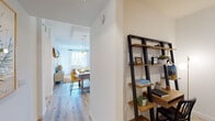 This thoughtfully laid-out single-floor residence combines modern design with functional living across several well-appointed spaces. Light hardwood flooring flows throughout, creating a cohesive and airy feel from room to room.

The kitchen stands out as a centerpiece of the home, featuring sleek flat-front cabinetry that extends to the ceiling, white quartz countertops, a stainless steel undermount sink, and a full suite of stainless steel appliances including a range, microwave, and refrigerator. Recessed lighting and under-cabinet lighting ensure the space is both practical and visually clean.

A hallway leads to an open dining area bathed in natural light from large windows, with stylish pendant lighting overhead adding warmth to the space. Adjacent to the entrance, a dedicated home office nook is outfitted with a leaning ladder shelving unit and a desk, offering a compact yet functional workspace.

The primary bedroom is serene and well-proportioned, featuring a ceiling fan, a large window dressed in sheer curtains that invite natural light, and light hardwood floors. The en-suite bathroom is finished with granite countertops, flat-panel cabinetry, large-format tile flooring, and direct access to a spacious walk-in closet with built-in shelving.

An additional bedroom and a flexible study or sitting room complete the layout, offering versatile options for occupants.