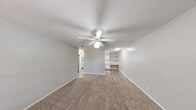 Located in Harlingen, TX, this single-story, one-bedroom, one-bathroom home offers a practical and well-organized layout designed for comfortable living. The living area features warm, neutral carpet flooring, a ceiling fan with integrated lighting, and a textured ceiling, creating a cozy and inviting atmosphere. Built-in shelving and a desk area along one wall add functional storage and workspace options. Natural light enters through windows fitted with blinds, lending the space a bright and airy feel.

The kitchen is efficiently arranged in an L-shaped configuration, outfitted with light wood-trimmed cabinetry, white countertops, and a full suite of white appliances including a range, refrigerator, and dishwasher. A window above the sink provides additional natural light.

The bedroom is a comfortable, well-proportioned room with soft carpet, a ceiling fan, and a window overlooking an outdoor area, offering natural light and ventilation. The hallway connects the rooms with smooth hardwood-style flooring, maintaining a clean transition throughout.

The bathroom features a wide vanity with a single sink, a large mirror with overhead lighting, and a tub-shower combination. A dedicated utility room rounds out the layout, adding practical storage or laundry functionality to this well-appointed home.