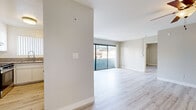 Located in the heart of West Hollywood at 1444 N Poinsettia Pl, this 2-bedroom, 2-bathroom residence offers a thoughtfully designed single-level layout with a clean, modern aesthetic throughout. Light wood-tone flooring runs continuously across all rooms, creating a cohesive and airy feel.

The combined living and kitchen area serves as the heart of the home. The living room is bright and open, anchored by large sliding glass doors that lead to a private balcony with views of mature trees and the surrounding neighborhood, flooding the space with natural light. A ceiling fan and wall-mounted mini-split unit provide year-round comfort.

The kitchen features white cabinetry, granite countertops, a full suite of appliances including a gas range and dishwasher, and a pass-through window that connects to the living area, enhancing the open flow.

The primary bedroom is generously proportioned, offering a mirrored sliding closet, a wall-mounted mini-split system, and a sliding glass door to a private balcony. The second bedroom also includes a mirrored closet and distinctive circular porthole-style windows that add architectural character. Both bathrooms are finished with granite vanity countertops and full tub-shower combinations.