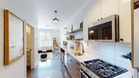 This thoughtfully designed single-floor unit blends modern aesthetics with functional living. The galley-style kitchen is a standout feature, outfitted with warm wood cabinetry, crisp white upper cabinets, and a classic white subway tile backsplash. Open shelving provides both display and storage space, while a stainless steel gas range, built-in microwave, undermount sink with a matte black faucet, and a full-size refrigerator complete the well-equipped cooking area. A built-in breakfast bar with metal stools offers a casual dining option along the kitchen's length. Polished concrete floors run throughout the unit, lending a sleek, contemporary feel that reflects natural light beautifully.

The bedroom is bright and inviting, benefiting from a large window that frames outdoor views and fills the room with natural light. A wall-mounted mini-split system provides climate control, and the space comfortably accommodates a full seating area alongside the sleeping area. The bathroom is clean and modern, featuring a long white vanity with open shelving, a large mirror, a glass-enclosed shower with vertical tile detailing, and polished concrete floors that echo the rest of the unit. Together, these spaces create a cohesive, well-appointed living environment with a distinctly urban, contemporary character.