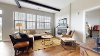 Located at Hayden Lofts in Dublin, Ohio, this two-bedroom, two-bathroom residence combines modern loft-inspired design with comfortable, functional living. The open-concept living area is an immediate highlight, featuring warm hardwood flooring, striking exposed ceiling beams, and a wall of large windows that flood the space with natural light. A sleek fireplace with a rustic wood mantel serves as a focal point, adding warmth and character to the room.

The kitchen is well-appointed with crisp white shaker cabinetry, dark granite countertops, stainless steel appliances, and hardwood flooring that continues seamlessly from the living area, reinforcing the cohesive, open feel of the main living space.

The primary bedroom is a comfortable retreat, carpeted for warmth, with generous natural light from large windows. Its en-suite bathroom features a full-wall tiled walk-in shower, wood-look flooring, and a clean, modern vanity. The second bedroom is equally well-lit and carpeted, served by a second full bathroom complete with a tub-shower combo. Both bedrooms are accompanied by dedicated closets with built-in shelving and hanging systems. Throughout, the residence balances industrial loft aesthetics with warm, inviting finishes.