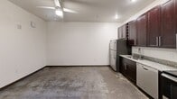 This two-story apartment at 144 4th St in Burlington, NC offers a well-designed layout spread across two comparable floors. The kitchen is outfitted with rich dark-wood cabinetry, granite countertops, and a full suite of stainless steel appliances including a refrigerator, dishwasher, range, and microwave. The open main living area features polished concrete floors and a ceiling fan, lending an urban, loft-inspired feel. Two bathrooms mirror the kitchen's design aesthetic, each featuring granite-topped dark vanities and clean white walls. The upper level showcases warm hardwood flooring, adding contrast and warmth to the space's contemporary character.