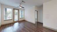 Located along North Central Expressway in Dallas, Texas, this single-story unit offers a well-designed layout with contemporary finishes throughout. Rich, dark wood-style flooring runs through the main living areas, creating a cohesive and polished aesthetic.

The kitchen is a standout space, featuring floor-to-ceiling dark espresso cabinetry with sleek hardware, light quartz countertops, and a green glass tile backsplash. A large center island with an undermount sink provides additional prep and storage space. Stainless steel appliances, including a French door refrigerator, electric range, built-in microwave, and dishwasher, complete the functional setup. Track lighting overhead brightens the workspace effectively.

The living area is bright and open, benefiting from natural light through multiple windows and a sliding glass door that provides outdoor access. A ceiling fan adds comfort and airflow to the space.

The bathrooms are finished with dark vanity cabinetry, white countertops, large mirrors, and tile surrounds. One bathroom connects directly to a spacious walk-in closet equipped with multiple hanging rods and shelving, offering generous storage capacity. An additional bedroom features carpet flooring and dual windows with views of surrounding greenery.