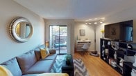 This single-floor apartment at Sandcastle Apartments offers a thoughtfully designed layout that maximizes functionality and comfort. The open-concept floor plan connects the main living spaces, creating a cohesive flow throughout the unit.

The living area serves as the heart of the apartment, featuring warm hardwood-style flooring and a textured ceiling. A sliding glass door floods the space with natural light while providing direct access to a private outdoor patio, offering views of the surrounding community. A built-in wall-mounted desk creates a dedicated workspace within the living area.

The kitchen features dark speckled countertops paired with light cabinetry, offering ample workspace and storage. The hardwood-style flooring continues seamlessly into this space, and a refrigerator is included among the appliances.

The bedroom is a calm, neutral retreat finished with plush carpeting and a textured ceiling. A window allows natural light to filter in, and the room conveniently connects to a walk-in closet, providing generous storage space.

The bathroom includes a full soaking tub and shower combination, accented by warm-toned tile surround, offering a clean and practical design. Throughout the apartment, neutral gray walls and consistent finishes contribute to a cohesive, modern aesthetic.