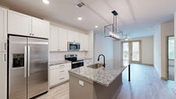 Located in Snellville, Georgia, this single-floor, 2-bedroom, 2-bathroom residence offers a thoughtfully designed layout with modern finishes throughout. The open-concept kitchen and living area serves as the heart of the home, showcasing crisp white shaker cabinetry, granite countertops, and a center island with a undermount sink and elegant pendant lighting overhead. Stainless steel appliances, including a French door refrigerator, electric range, and built-in microwave, complete the kitchen. Light wood-style flooring runs throughout the main living areas, adding warmth and continuity.

Both bedrooms are carpeted for comfort and feature ceiling fans and generous natural light. Each bedroom is served by its own closet, with the primary suite offering a spacious walk-in closet with wire shelving. The primary bathroom includes a dual-sink vanity with white countertops, framed mirrors with contemporary sconce lighting, and a glass-enclosed shower. A dedicated laundry area adds everyday convenience.

French doors in the living area open to a private patio, framed by landscaped greenery and black ornamental fencing — a peaceful outdoor retreat within the broader community setting.