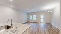 Located at 1004 Wildflower in Wilmington, NC, this two-story home offers three bedrooms and four bathrooms across two well-proportioned floors. The main level features an open-concept layout that seamlessly combines the living room, dining area, and kitchen into a single welcoming space. The kitchen is appointed with granite countertops, white cabinetry with sleek hardware, stainless steel appliances, and light hardwood-style flooring that carries throughout the main living areas. A ceiling fan overhead and multiple windows allow ample natural light to fill the living space, which also provides access to the exterior via a glass-panel door. A pantry and laundry room add everyday convenience on this level, along with an attached garage featuring an automatic opener. Upstairs, three bedrooms offer comfortable accommodations, including a generously sized primary bedroom with vaulted ceilings, abundant natural light, and a walk-in closet equipped with wire shelving systems. Additional closets are distributed throughout for excellent storage. The bathrooms are finished in a clean, neutral palette. Consistent light hardwood-style flooring, crisp white trim, and a soft neutral wall palette give the entire home a bright, cohesive, and move-in-ready aesthetic.