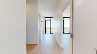 Located in Phoenix, AZ, this contemporary high-rise unit offers a sophisticated open-concept layout spread across a single floor. Light wood-tone flooring flows throughout, complementing the crisp white walls and creating a clean, modern aesthetic.

The expansive living area is anchored by a ceiling fan and recessed lighting, with floor-to-ceiling windows and glass-paneled balcony doors that bathe the space in abundant natural light. The balcony offers breathtaking panoramic views of the Phoenix skyline, surrounding neighborhoods, and distant mountain ranges.

The sleek, modern kitchen features light wood cabinetry with matte black hardware, a gas cooktop, stainless steel double ovens, a white quartz island with an undermount sink, and a mosaic tile backsplash. Pendant lighting above the island adds a refined finishing touch.

The bedrooms are generously proportioned, each benefiting from large floor-to-ceiling windows that frame striking elevated city views. Wide hallways connect the rooms, enhancing the sense of openness throughout.

The bathrooms are finished to a high standard, featuring floating wood-tone vanities with white quartz countertops, large-format tile flooring, and a glass-enclosed walk-in shower with mosaic tile flooring and white wall tile. Every detail reflects a consistent, contemporary design sensibility.