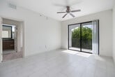 This 1,090-square-foot unit at 925 NW 97th Ave, Miami, FL offers a single-story layout with 4 bedrooms and 2 bathrooms. The open-concept kitchen features rich wood cabinetry, dark granite countertops, a central island, stainless steel appliances including a French door refrigerator and range, and track lighting overhead. Large-format white tile flooring extends throughout the main living areas, creating a bright, cohesive aesthetic.

The four bedrooms are finished with neutral carpet and receive natural light through slatted window blinds. The primary bedroom, at 150 square feet, includes a ceiling fan and sliding glass doors opening to a private balcony overlooking lush tropical landscaping with palm trees and manicured grounds. Both bathrooms are finished with large-format white wall tiles, soaking tubs with shower combinations, wood-toned vanities, and dark granite countertops, maintaining a consistent design language throughout.

Two dedicated closets provide additional storage. The unit's light-toned walls, natural light, and tropical outdoor views contribute to a clean, functional living environment well-suited to Miami's climate and lifestyle.