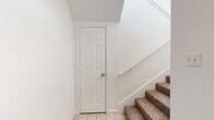 This two-story home in Taylor, TX offers a practical and well-organized layout across two levels. The ground floor provides direct access to an attached garage equipped with an automatic opener, alongside a welcoming entrance with tile flooring and carpeted stairs leading to the main living level above. The upper floor hosts the majority of the living space, where an open-concept kitchen and living room serve as the heart of the home. The kitchen features light wood cabinetry with warm trim accents, a double sink, electric range, built-in microwave, and a dishwasher, all set on durable light wood-look flooring. An arched window in the adjoining living area brings in natural light, creating a bright and airy atmosphere. Both bedrooms are carpeted and finished with crisp white walls, offering comfortable and versatile spaces. The primary bedroom is generously sized and provides ample room for furnishings. A hallway connects the upper-level rooms, with built-in closet storage visible in one of the secondary spaces. The two bathrooms include light wood vanity cabinetry, white countertops, large mirrors, and tub-shower combinations with tile surrounds, all accented by light wood-look flooring. The home presents a clean, neutral aesthetic throughout, making it move-in ready.