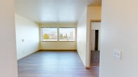 Located on the third floor at 245 Tacoma Ave S in downtown Tacoma, Washington, this two-bedroom, one-bathroom apartment offers a functional and comfortable layout across a single floor. The living room is bright and airy, featuring light hardwood-style flooring and a pair of large windows that frame views of the surrounding Tacoma cityscape and lush tree canopy, filling the space with natural light. The kitchen is well-appointed with light maple cabinetry, dark laminate countertops, a peninsula for additional prep space or casual dining, and a full suite of white appliances including a range, microwave, dishwasher, and refrigerator. Track lighting illuminates the kitchen area effectively. Both bedrooms are carpeted and feature individual closets with built-in shelving for ample storage. The primary bedroom includes dual windows offering sweeping city views, while the secondary bedroom also benefits from natural light through its own window. The bathroom is clean and straightforward, featuring a tiled tub-shower combination with chrome fixtures. Hardwood-style flooring flows throughout the main living areas, contributing to a cohesive and well-maintained aesthetic throughout this centrally located Tacoma residence.