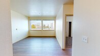 Located on the third floor at 245 Tacoma Ave S in downtown Tacoma, Washington, this two-bedroom, one-bathroom apartment offers a functional and comfortable layout across a single floor. The living room is bright and airy, featuring light hardwood-style flooring and a pair of large windows that frame views of the surrounding Tacoma cityscape and lush tree canopy, filling the space with natural light. The kitchen is well-appointed with light maple cabinetry, dark laminate countertops, a peninsula for additional prep space or casual dining, and a full suite of white appliances including a range, microwave, dishwasher, and refrigerator. Track lighting illuminates the kitchen area effectively. Both bedrooms are carpeted and feature individual closets with built-in shelving for ample storage. The primary bedroom includes dual windows offering sweeping city views, while the secondary bedroom also benefits from natural light through its own window. The bathroom is clean and straightforward, featuring a tiled tub-shower combination with chrome fixtures. Hardwood-style flooring flows throughout the main living areas, contributing to a cohesive and well-maintained aesthetic throughout this centrally located Tacoma residence.