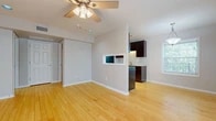 This thoughtfully laid-out 1-bedroom, 1-bathroom unit offers a cohesive and functional design highlighted by warm bamboo hardwood flooring that runs throughout the entire space. The open living area is bright and airy, benefiting from natural light through large windows with blinds, and is equipped with a ceiling fan for year-round comfort. A half-wall with a pass-through window connects the living room to the galley-style kitchen, which features rich dark espresso cabinetry, granite countertops, a stainless steel sink, and a full suite of stainless steel appliances including a gas range, microwave, and refrigerator. The bedroom is comfortably sized with its own ceiling fan, a window overlooking lush greenery, and convenient access to a generously sized walk-in closet with dual hanging rods and shelving. The bathroom is well-appointed with dark wood cabinetry, a granite vanity top, large-format travertine tile flooring and wall surround, and a soaking tub with a curved shower rod. Neutral gray walls and white trim throughout create a clean, modern aesthetic, while the efficient layout makes excellent use of every square foot of living space.