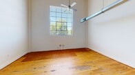 Located at 614 Lynn St in Danville, Virginia, this two-bedroom, two-bathroom residence spans two floors, offering a well-organized layout with a generous main level and a more intimate upper level. The main floor hosts the kitchen, living areas, and supporting rooms, while the upper floor provides a private retreat. Throughout the space, warm hardwood flooring adds character and continuity, complementing the clean white walls and bright, airy atmosphere.

The kitchen is a functional highlight, featuring rich wood cabinetry, light countertops, subway tile backsplash, and full appliances including a range, dishwasher, and refrigerator. Notably high ceilings with exposed industrial ductwork and pendant lighting give this area a loft-like quality. Large grid-pane windows in the main living area allow abundant natural light and offer views of the surrounding greenery, enhanced by exposed white brick walls and ceiling fans.

The spacious primary bedroom includes an en-suite bathroom and ceiling fan, with light hardwood flooring providing a refreshed feel. The second bedroom also features hardwood floors and a ceiling fan. Both bathrooms are finished with clean white tub-shower combinations and wood-accented vanities. A walk-in closet adds practical storage to the primary suite, rounding out this well-appointed, character-rich residence.