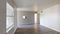 This single-story, 3-bedroom, 2-bathroom home offers a thoughtfully designed layout that maximizes every square foot. The combined living room and kitchen area forms the heart of the home, where durable wood-style vinyl plank flooring flows throughout the main living spaces, complemented by neutral gray walls and clean white baseboards that create a bright, modern aesthetic. Natural light enters through slatted blinds, enhancing the open feel of the living area.

The galley-style kitchen features white cabinetry, light countertops, a stainless steel sink, and black appliances including an electric range, refrigerator, and dishwasher. A pass-through window connects the kitchen to the living area, adding a sense of openness between the two spaces.

The bedrooms are carpeted for comfort, with ceiling fans providing year-round climate control. The primary bedroom is generously sized and includes dual closets, offering ample storage. The additional bedrooms are well-proportioned and share a clean, functional hallway layout. Both bathrooms are finished with light vinyl flooring, white vanities, and tub-shower combinations, maintaining a consistent and clean design throughout.

A hallway and dedicated closet round out the functional layout of this efficiently designed single-floor home.