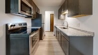 Located at 1570 E Saint Germain St in Saint Cloud, Minnesota, this single-floor unit offers a practical and updated layout designed for comfortable everyday living. The galley-style kitchen is a standout feature, showcasing dark cabinetry paired with granite-look countertops, a stainless steel sink, and a full suite of stainless steel appliances including an electric range, microwave, dishwasher, and refrigerator. Light wood-style luxury vinyl flooring runs through the kitchen and living areas, lending a clean, modern aesthetic throughout. The living space is bright and open, featuring a textured ceiling, neutral white walls, baseboard heating, and a window that allows natural light to fill the room. A secondary room — ideal as a bedroom or flex space — continues the light flooring and offers additional window views to the outdoors. The carpeted bedroom provides a softer, quieter retreat, also featuring a window with natural light and baseboard heating. The bathroom is finished with wood-style tile flooring, a granite-top vanity, and a full tub/shower combination with chrome fixtures. The overall design is clean and neutral, offering a move-in-ready space with updated finishes throughout.