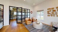 This single-floor amenity facility offers a thoughtfully designed collection of spaces that balance recreation, productivity, and comfort. The centerpiece is a spacious game room highlighted by a full-size pool table, a warm brick fireplace, wall-mounted displays, and a dramatic skylight that floods the area with natural light. Built-in shelving and a lounge seating nook add character and functionality to the space.

The fitness center is generously proportioned, outfitted with a comprehensive selection of cardio equipment including treadmills, ellipticals, and strength machines. Large windows along the perimeter invite natural light and offer outdoor views, while a colorful geometric carpet adds a modern, energetic feel underfoot.

Multiple office and workspace areas are distributed throughout the facility. Wide-plank hardwood flooring anchors these rooms, which feature clean white walls, recessed lighting, and ample desk configurations. A standout feature is a striking full-height natural stone accent wall that lends rustic warmth to one of the workspaces.

The lounge area provides an inviting retreat with leather and upholstered seating, a patterned area rug, and abundant natural light through large windows. A set of elegant black-framed glass folding doors connects the lounge to an adjoining stone-accented dining or conference space, creating a seamless, sophisticated flow throughout the facility.