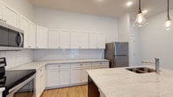 Located at 8900 Lyra Dr in Columbus, Ohio, this single-story space offers a clean, contemporary design with thoughtful finishes throughout. The kitchen stands out as a centerpiece of the home, showcasing crisp white shaker-style cabinetry that extends to the upper walls, providing generous storage capacity. A classic white subway tile backsplash adds texture and timeless character, complementing the light-toned granite countertops that feature subtle speckled detailing. A large central island with a matching granite surface offers additional workspace and a natural gathering point. Stainless steel appliances, including a full-size refrigerator, complete the kitchen's modern, functional aesthetic. The warm hardwood-style flooring grounds the space and flows seamlessly underfoot, while recessed lighting illuminates the room with a bright, welcoming atmosphere. The overall color palette — whites, light grays, and warm wood tones — creates a fresh and airy ambiance throughout. The layout is designed with practicality in mind, offering a well-organized flow that suits both everyday living and entertaining. This space at 8900 Lyra Dr presents a polished, move-in-ready environment in a convenient Columbus location.