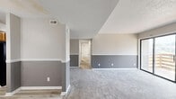 Located at 2301 Arkansas Blvd in Texarkana, AR, this single-story, 3-bedroom, 2-bathroom home offers a well-organized and functional layout. The living area features a distinctive two-tone gray wall treatment with white chair rail molding, plush carpeting, a textured ceiling, and a fireplace flanked by sliding glass doors that open to a private balcony with outdoor views. The combined kitchen and dining area is equipped with warm wood cabinetry, light countertops, a stainless sink, and durable wood-look flooring that extends throughout the non-carpeted areas. The bedrooms are carpeted and each features ceiling fans with light fixtures and window treatments that allow for natural light. The primary bedroom provides a comfortable, well-proportioned retreat. Both bathrooms are finished with light-toned vanities, stone-look countertops, and wood-look flooring. A dedicated laundry room accommodates a full-size washer and dryer. Three closets offer ample storage throughout the home. A central hallway connects the main living spaces to the private quarters, creating a clear and practical flow. The overall aesthetic is neutral and clean, with consistent finishes throughout.