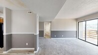 Located at 2301 Arkansas Blvd in Texarkana, AR, this single-story, 3-bedroom, 2-bathroom home offers a well-organized and functional layout. The living area features a distinctive two-tone gray wall treatment with white chair rail molding, plush carpeting, a textured ceiling, and a fireplace flanked by sliding glass doors that open to a private balcony with outdoor views. The combined kitchen and dining area is equipped with warm wood cabinetry, light countertops, a stainless sink, and durable wood-look flooring that extends throughout the non-carpeted areas. The bedrooms are carpeted and each features ceiling fans with light fixtures and window treatments that allow for natural light. The primary bedroom provides a comfortable, well-proportioned retreat. Both bathrooms are finished with light-toned vanities, stone-look countertops, and wood-look flooring. A dedicated laundry room accommodates a full-size washer and dryer. Three closets offer ample storage throughout the home. A central hallway connects the main living spaces to the private quarters, creating a clear and practical flow. The overall aesthetic is neutral and clean, with consistent finishes throughout.