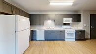 Located at 1223 E Eighth Street in Traverse City, Michigan, this two-bedroom, one-bathroom unit offers a well-designed single-floor layout with modern finishes throughout. The open-concept kitchen, dining, and living area serves as the heart of the home, featuring gray shaker-style cabinetry, white countertops, a full suite of white appliances including a refrigerator, range, microwave, and dishwasher, complemented by light wood-look flooring that extends throughout the main living spaces. The kitchen provides ample cabinet storage and flows seamlessly into the combined dining and living area, creating a functional and cohesive space for everyday living. Both bedrooms are carpeted and receive natural light through large windows with views of surrounding greenery. The primary bedroom includes a closet and connects conveniently to the rest of the unit. A third closet provides additional storage flexibility. The bathroom is equipped with a walk-in shower featuring grab bars, a gray vanity with white countertop, and wood-look tile flooring. In-unit laundry adds everyday convenience. One bedroom opens to a private balcony, offering pleasant outdoor views of mature trees.