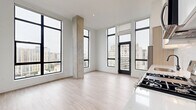 Located at 1156 Delaware St in Denver's vibrant Lincoln Park neighborhood, this modern one-bedroom, one-bathroom residence offers a thoughtfully designed single-floor layout. The open-concept living area makes a striking first impression with floor-to-ceiling black-framed windows that flood the space with natural light and frame sweeping views of the Denver skyline. An exposed concrete structural column adds an industrial character that complements the clean, contemporary aesthetic throughout.

Light wood-look flooring runs seamlessly across the living room, kitchen, bedroom, and hallway. The kitchen is well-appointed with stainless steel appliances including a gas range, built-in microwave, and French door refrigerator, alongside two-tone cabinetry in white and natural wood, a subway tile backsplash, and a sleek undermount sink with a matte black faucet.

The bedroom continues the floor-to-ceiling window theme with a ceiling fan and additional city views, while three closets provide generous storage. The bathroom features warm wood vanity cabinetry, a white countertop, matte black hardware, and a relaxing soaking tub. A dedicated laundry area and private balcony round out this well-equipped urban residence.