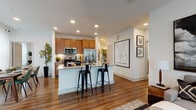 Located at 2701 N Austin Ave in Georgetown, Texas, this single-story residence offers a thoughtfully designed layout with a cohesive, modern aesthetic throughout. Rich hardwood-style flooring flows through the main living areas, anchoring the open-concept design and creating a warm, inviting atmosphere.

The kitchen is a functional centerpiece, outfitted with stainless steel appliances, including a range, over-the-range microwave, and French door refrigerator. Warm wood cabinetry pairs with granite-style countertops and a tile backsplash, while a peninsula with bar seating provides a casual dining and gathering space. Recessed lighting illuminates the area effectively.

Adjacent to the kitchen, a dedicated dining area benefits from generous natural light through large windows dressed with sheer curtains, creating a bright and airy atmosphere. The living room offers a comfortable, well-lit space with large windows and room for a variety of furniture arrangements.

The bedroom features plush carpeting, a ceiling fan, and access to a walk-in closet outfitted with multiple hanging rods and shelving for organized storage. The bathroom includes a wood vanity with granite countertops, a tub-shower combination, and hardwood-style flooring. A dedicated laundry area accommodates a full-size washer, completing the home's practical amenities.