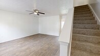 Located at 11501 Harts Rd in Jacksonville, FL, this two-story home offers a practical and comfortable layout across two floors. The main level features a welcoming living room with wood-look flooring, a ceiling fan, and a textured ceiling, complemented by natural light from a front-facing window with outdoor views. The kitchen is well-equipped with light gray cabinetry, a double sink, white appliances including a range and refrigerator, light countertops, and an adjacent open pantry for additional storage. Three full bathrooms are distributed throughout the home, each featuring a tub-shower combination, wood-look flooring, and vanities with marble-style countertops. The upper floor houses the bedrooms, including a generously sized primary bedroom. The secondary bedrooms feature soft carpet flooring and windows that bring in natural light. Each floor is connected by a carpeted staircase. Additional features include three closets for ample storage and a dedicated laundry room. The home's clean white walls and neutral finishes throughout create a bright, move-in ready environment suited for a variety of living arrangements.