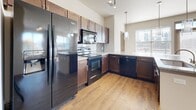Located at 909 Rosa L Parks Blvd in Nashville, TN, this single-floor unit offers a well-designed layout with a thoughtful blend of materials and finishes throughout. The open-concept kitchen serves as a central hub, showcasing rich dark wood cabinetry, granite countertops, a subway tile backsplash, and a full suite of black appliances including a refrigerator, range, microwave, and dishwasher. Pendant lighting above the extended kitchen island adds a modern touch, while hardwood-style flooring extends through the main living areas, enhancing the warmth and continuity of the space. The living area is bathed in natural light through multiple large windows fitted with horizontal blinds, offering views of the Nashville skyline — a striking backdrop that adds character to the space. Ceiling fans provide comfort throughout. The bedrooms feature plush carpeting and bright windows, creating comfortable, restful retreats. Two bathrooms are finished with granite vanity tops, rich wood cabinetry with brushed nickel hardware, and hardwood-style flooring. One bathroom includes a tiled soaking tub and shower combination, while the other features a walk-in shower. The neutral color palette and clean architectural lines give the entire space a cohesive, contemporary feel.