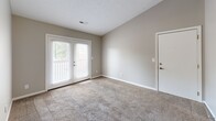 Located at 374 Elston Rd in Lafayette, Indiana, this single-story, 2-bedroom, 1-bathroom home offers a practical and efficient layout. The interior is finished with a neutral gray color palette and textured ceilings throughout, creating a clean and cohesive aesthetic.

The galley-style kitchen is a standout feature, equipped with warm wood cabinetry, white appliances including a refrigerator, range, and dishwasher, and a double sink. Rich, dark hardwood-style flooring adds a polished contrast to the light countertops and walls.

Both bedrooms are carpeted in a warm beige tone and feature windows with blinds that allow for natural light and outdoor views of the surrounding greenery. The primary bedroom is notably spacious, offering a walk-in closet outfitted with wire shelving and hanging rods for ample storage. The second bedroom also includes a standard closet with a built-in shelf and rod.

A connecting hallway links the bedrooms to the shared bathroom, which features the same dark hardwood-style flooring as the kitchen. The living area benefits from French doors that open to an outdoor space, filling the room with natural light and providing direct exterior access. The home's straightforward, functional design makes it a comfortable and practical residence.