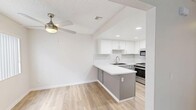 Located at 1300 N L St. in Lompoc, CA, this single-story 2-bedroom, 1-bathroom home offers a clean, modern aesthetic throughout its thoughtfully laid-out floor plan. The kitchen is a standout feature, showcasing two-tone cabinetry with white uppers and gray lowers, a white subway tile backsplash, white quartz countertops, stainless steel appliances including a gas range, microwave, and refrigerator, and a peninsula that opens toward the living area. Light wood-style flooring runs through the kitchen and living spaces, enhancing the bright, airy feel. One of the living areas features a sliding glass door that fills the room with natural light and provides outdoor access, while a ceiling fan adds comfort overhead. Both bedrooms are carpeted and offer a calm, neutral palette, each equipped with sliding double-door closets providing ample storage. The space includes an impressive total of six closets, ensuring abundant organization options throughout. The bathroom is finished with the same light wood flooring, featuring a tub-shower combination and clean, minimal styling. Textured ceilings are present throughout, adding subtle architectural character to this move-in-ready home.