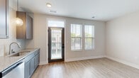 Located at 800 E Long Street in Columbus, Ohio, this one-bedroom, one-bathroom unit offers a thoughtfully designed layout that maximizes its compact footprint. The open-concept living and kitchen area is anchored by light-toned hardwood-style flooring and neutral walls, creating a bright and cohesive atmosphere. A glass-paneled entry door, flanked by two large windows with horizontal blinds, allows ample natural light to fill the main living space while offering views of the surrounding neighborhood.

The kitchen is a standout feature, showcasing gray shaker-style cabinetry, granite countertops, a subway tile backsplash, and a full suite of stainless steel appliances including a range, microwave, dishwasher, and refrigerator. Recessed and pendant lighting adds functional illumination throughout.

The bedroom is carpeted for comfort and features neutral gray walls, a dedicated closet with a bold black sliding panel door and built-in rod, providing practical storage. The bathroom is clean and modern, with a large sliding-glass walk-in shower, granite vanity, and matching gray cabinetry consistent with the overall design palette. The unit presents a cohesive, contemporary aesthetic throughout.