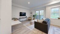 Located at 137 Keith Rd E in North Vancouver, this thoughtfully designed unit makes excellent use of its compact single-floor layout. The living room serves as the heart of the space, featuring light-toned hardwood-style flooring, white walls, and recessed lighting that contribute to a clean, contemporary aesthetic. Large sliding doors lead to a private balcony, allowing natural light to fill the room and offering views of the surrounding neighbourhood. A built-in Murphy bed with integrated shelving and a fold-down desk demonstrates the unit's smart approach to multifunctional living, seamlessly blending sleeping and living areas without sacrificing style or practicality.

The kitchen is finished to a modern standard, showcasing white cabinetry with sleek hardware, a taupe quartz countertop, a deep stainless steel undermount sink, and a vertically laid ceramic tile backsplash in muted grey tones that adds visual texture and depth.

The bathroom maintains the unit's cohesive, neutral palette with large-format beige floor tiles, white wall tiles, and a full soaking tub fitted with a sliding rail shower. Clean lines and bright surfaces give the room an open, well-appointed feel. Overall, the space offers a refined, modern atmosphere suited for comfortable single-occupant living.
