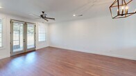 Located at 22052 Stratford Way in Athens, Alabama, this two-story home offers three bedrooms and three bathrooms across a well-distributed layout. The main floor comprises the majority of the living space and includes a combined kitchen and living room, an attached garage with an automatic opener, and connecting hallways. The kitchen is outfitted with light gray cabinetry featuring matte black hardware, white quartz countertops, a subway tile backsplash, stainless steel appliances, and warm hardwood-style flooring that flows throughout the main living areas. A set of French doors with flanking windows floods one room with natural light and provides outdoor access. The upper floor houses the primary bedroom, a generously sized retreat with plush carpeting, crown molding, a ceiling fan, and a direct en-suite bathroom. Additional bedrooms also feature carpet and closets with paneled doors. The bathrooms are well-appointed, showcasing large-format tile surrounds, dark-framed glass shower enclosures, and white vanities with matching hardware. Throughout the home, a consistent palette of crisp white walls, clean trim work, and warm flooring creates a cohesive, move-in-ready aesthetic.