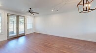 Located at 22052 Stratford Way in Athens, Alabama, this two-story home offers three bedrooms and three bathrooms across a well-distributed layout. The main floor comprises the majority of the living space and includes a combined kitchen and living room, an attached garage with an automatic opener, and connecting hallways. The kitchen is outfitted with light gray cabinetry featuring matte black hardware, white quartz countertops, a subway tile backsplash, stainless steel appliances, and warm hardwood-style flooring that flows throughout the main living areas. A set of French doors with flanking windows floods one room with natural light and provides outdoor access. The upper floor houses the primary bedroom, a generously sized retreat with plush carpeting, crown molding, a ceiling fan, and a direct en-suite bathroom. Additional bedrooms also feature carpet and closets with paneled doors. The bathrooms are well-appointed, showcasing large-format tile surrounds, dark-framed glass shower enclosures, and white vanities with matching hardware. Throughout the home, a consistent palette of crisp white walls, clean trim work, and warm flooring creates a cohesive, move-in-ready aesthetic.