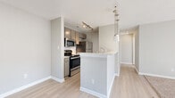 Located at 8200 Riverbirch Dr in Charlotte, NC, this one-bedroom, one-bathroom residence offers a thoughtfully designed single-floor layout that maximizes comfort and functionality. The open-concept kitchen and living area serves as the heart of the home, featuring light wood-style flooring that flows seamlessly throughout. The kitchen is equipped with a full suite of stainless steel appliances, including a range, microwave, refrigerator, and dishwasher, complemented by sleek taupe cabinetry, white countertops, and a peninsula with pendant lighting that doubles as a breakfast bar. The living area transitions naturally from the kitchen, with neutral gray walls and a window that brings in warm natural light. The spacious bedroom features plush wall-to-wall carpeting, large windows with blinds, and a sliding glass door that fills the room with sunlight. The bathroom is cleanly finished with wood-style flooring, a white vanity, and a full tub-shower combination accented by large-format marble-look tile surround. Soft, neutral tones are carried consistently throughout the unit, creating a cohesive and calming ambiance well-suited for modern living.