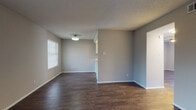Located at 1501 Kinney Ave in Austin, TX, this single-story home offers a clean, modern aesthetic throughout its well-appointed layout. Dark hardwood-style flooring runs consistently across the living spaces and bedrooms, providing a warm, cohesive look that complements the neutral gray wall tones and crisp white trim.

The open living and dining area is bathed in natural light from multiple windows fitted with horizontal blinds, creating a bright and airy atmosphere. A flush-mount ceiling light and textured ceilings add functional and visual character to the space. A pass-through opening connects the living area to the kitchen, enhancing the sense of openness.

The galley-style kitchen is efficiently designed with ample white shaker cabinetry, light countertops, and a tasteful subway tile backsplash in a warm earthy tone. Black and stainless steel appliances — including a gas range and refrigerator — are included, and track lighting overhead ensures excellent task illumination.

The bedrooms continue the dark flooring theme and feature generous closet space, including sliding-door and standard closets with built-in hanging rods. The rooms are well-proportioned with neutral walls suited to a variety of uses.

Situated in Austin's vibrant 78704 corridor, this home combines practical design with a clean, updated interior finish throughout.