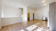 This well-appointed two-story residence offers a clean, modern aesthetic with thoughtfully designed living spaces across both floors. The main level features an open-concept layout with soaring ceilings that lend an airy, expansive feel. Light wood-tone flooring runs throughout, complemented by crisp white walls and recessed lighting. A ground-floor half bathroom and a dedicated storage closet add everyday convenience near the main entrance.

The kitchen is outfitted with stainless steel appliances — including a refrigerator, range, microwave, and dishwasher — paired with two-tone cabinetry featuring white upper cabinets and wood-grain lower cabinets set against a classic subway tile backsplash. An open staircase with a white balustrade connects the main floor to the upper level.

Upstairs, the bedrooms are carpeted for comfort and filled with natural light through generous windows. The primary suite includes a walk-in closet with built-in shelving and hanging rods, as well as a private en-suite bathroom appointed with large-format marble-look tile flooring, a dual-sink vanity with wood-grain cabinetry, a frameless glass walk-in shower, and a wide illuminated mirror. A dedicated in-unit laundry space with a front-loading washer completes the upper floor.