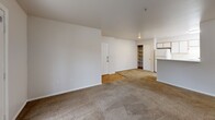 This 560 square foot apartment in Beaverton, Oregon, offers a well-designed living space on a single floor. The unit features one bedroom measuring 130 square feet, complemented by two full bathrooms for added convenience. The living area is open and bright, with a large window providing natural light and views of the outdoors. Carpeting in the living room and bedroom adds warmth, while the kitchen and bathroom areas boast practical hardwood flooring.

The apartment includes a dedicated laundry space with a modern washing machine, enhancing the unit's functionality. Storage is addressed with a built-in closet, optimizing the use of available space. A balcony accessible through French doors extends the living area outdoors, offering a pleasant spot for fresh air and relaxation.

The kitchen, though not fully visible in the images, appears to be integrated into the main living space, promoting an open-concept feel. Both bathrooms are efficiently designed, with one featuring a bathtub-shower combination and the other a vanity with ample counter space. The overall decor maintains a neutral palette, creating a clean and versatile canvas for personal styling. This apartment combines comfort and practicality in a compact, well-laid-out space.