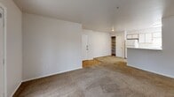 Located in Beaverton, Oregon, this one-bedroom, one-bathroom residence offers a practical and well-organized single-floor layout. The open-concept living area seamlessly combines the dining room, kitchen, and living room into one cohesive space. The kitchen features white cabinetry, a peninsula with a breakfast bar, white appliances including a refrigerator and range, and hardwood-style flooring. The living area is finished with plush carpet and provides direct access to a private balcony through a glass-paneled door, offering views of surrounding greenery. The bedroom is a comfortable, carpeted retreat with a large window that brings in natural light and frames outdoor tree views. It includes two closets — one of which is a walk-in — providing generous storage. The full bathroom features a tub/shower combo with white tile surround, a vanity with cabinet storage, and warm hardwood-style flooring. A dedicated laundry room with a front-load washer and overhead shelving adds everyday convenience. Additional storage is provided by a pantry and hallway closet, rounding out this efficiently designed and functional living space.