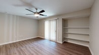 This 1-bedroom, 1-bathroom residence is thoughtfully designed to maximize comfort and functionality across a single floor. The open living room features warm wood-look luxury vinyl plank flooring, a ceiling fan with light fixture, and a sliding glass door with vertical blinds that floods the space with natural light. A set of built-in open shelves adds practical storage and display options directly in the living area.

The galley-style kitchen is outfitted with crisp white shaker cabinetry, marble-look countertops, a stainless steel sink, and black appliances including an electric range and refrigerator. Recessed lighting and additional built-in shelving enhance both function and style in this efficiently designed space.

The bedroom is carpeted for comfort and benefits from multiple windows that bring in natural light. A ceiling fan overhead and two closets — providing generous storage — round out this well-sized retreat.

The bathroom is clean and modern, featuring white cabinetry with brushed nickel hardware, a marble-look vanity top, a full tub/shower combination with large-format tile surround, and wood-look flooring that ties in with the rest of the home. A hallway connects the main areas, completing this cohesive and move-in-ready floor plan.