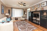 This single-floor residence at 5750 Buffington Rd in Union City, Georgia offers a thoughtfully designed open-concept layout finished with warm neutral tones throughout. Rich hardwood flooring runs through the main living areas, complemented by crisp white crown molding and baseboards that add a polished, classic touch.

The living area flows seamlessly into a peninsula-style kitchen, which features warm wood cabinetry, dark granite-style countertops, and black appliances. The open sightlines connect the kitchen directly to the dining area, where an elegant arched entryway, a pendant light fixture, and a decorative round mirror create a refined and intimate atmosphere.

The bedroom is a comfortable retreat, fitted with plush carpeting, a ceiling fan, and a generously sized window that allows natural light to pour in while offering views of the surrounding greenery. The neutral wall tones and wall art details contribute to a calm, restful ambiance.

The bathroom is well-equipped with hardwood flooring, a tub-shower combination, a dark-topped vanity with warm wood cabinetry, and bright overhead lighting above a large mirror. The overall design of the space balances practicality with aesthetic cohesion, making it a functional and inviting home.