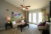 Located at 4133 Shoreline Cir in Virginia Beach, VA, this single-floor residence offers a thoughtfully designed layout with a warm, welcoming ambiance throughout. The living room is a standout space, anchored by a classic white-mantel fireplace with a dark surround and complemented by soaring vaulted ceilings that lend an impressive sense of openness. French doors flood the room with natural light and provide direct outdoor access. Plush carpeting runs throughout the main living areas, adding comfort underfoot. Adjacent to the living room, the dining area features an overhead chandelier and a large window, creating a bright and inviting setting for meals. The kitchen is equipped with rich wood cabinetry, granite-style countertops, tile flooring, and full appliances including a range and refrigerator, offering ample storage and prep space. Two well-sized bedrooms provide comfortable retreats, each with carpeted floors, natural light, and generous closet space. The bathroom is cleanly finished with tile flooring, a tub-shower combination, and a wood-vanity with a white countertop. A dedicated in-unit laundry area with a full-size washer and dryer adds everyday convenience to this well-rounded Virginia Beach home.