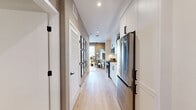 Located at 4888 Convoy Street in San Diego's Kearny Mesa neighborhood, this well-appointed one-bedroom, one-bathroom residence offers a smart, efficient layout across a single floor. Light oak-toned flooring flows throughout, creating a cohesive and warm aesthetic from entry to living area.

The entryway hallway introduces the home with clean lines, white shaker-style cabinetry, and modern matte-black hardware accents. The kitchen is neatly integrated along the hallway, featuring stainless steel appliances, a full-size refrigerator, and ample storage.

The living room is a refined, intimate space highlighted by textured wall treatments, recessed lighting, and a striking floor-to-ceiling sliding glass door that opens to a private balcony — flooding the room with natural light and offering open outdoor views of the surrounding San Diego skyline.

The bedroom carries a sophisticated ambiance with grasscloth-style accent walls, a statement tiered glass chandelier, brass wall sconces, and a mirrored sliding closet that enhances the sense of space. The design is both functional and visually elevated.

The bathroom is crisp and minimal, outfitted with a soaking tub and shower combination enclosed by sliding glass doors, a white vanity, and consistent light wood flooring that ties the space together. Every room reflects a cohesive, contemporary design sensibility.