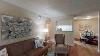 This single-floor residence offers a practical and well-organized layout with two bedrooms and one and a half bathrooms. The living area serves as the heart of the home, featuring warm hardwood-style flooring, neutral-toned walls, and a textured ceiling. Natural light filters through blinds-covered windows, lending a comfortable ambiance to the space. A pass-through window connects the living area to the kitchen, enhancing the open feel between the two spaces.

The kitchen is efficiently arranged with white cabinetry, laminate countertops, a double-basin sink, and white appliances including a range and refrigerator. The hardwood-style flooring continues here, maintaining visual consistency throughout the main living spaces.

Both bedrooms are carpeted and offer a quiet, cozy atmosphere. The primary bedroom includes a ceiling fan and direct access to a bathroom, while the second bedroom is served by a window that allows natural light. Each bedroom features closet space and textured ceilings consistent with the rest of the home.

The 1.5 bathrooms include a full bath with a shower and a half bath, both finished with neutral tones and functional fixtures. Overall, the space presents a cohesive, comfortable layout suited for everyday living.