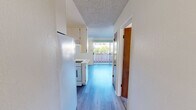 Located at 2710 Spyglass Dr in the coastal city of Pismo Beach, California, this one-bedroom, one-bathroom unit offers a well-organized and efficient single-floor layout. The living area features smooth luxury vinyl plank flooring and a ceiling fan with light fixture, creating a bright and airy atmosphere. A sliding glass door opens to a private balcony, allowing natural light to pour in while providing a pleasant outdoor retreat with greenery views. The kitchen flows seamlessly from the living space and is equipped with white cabinetry extending to the ceiling for ample storage, a peninsula with a built-in sink and light countertops, and a refrigerator. A textured popcorn ceiling is consistent throughout the unit. The bedroom is carpeted for comfort and features a large sliding wood-panel closet alongside an additional door for extra storage. A window with sheer curtains allows natural light into the room. The bathroom includes a full-width mirror, a speckled countertop vanity, and a clean, functional design. Throughout the unit, warm neutral wall tones contribute to a calm and cohesive aesthetic well-suited to the relaxed coastal lifestyle of Pismo Beach.