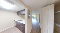 Located in Hialeah, FL, this well-designed one-bedroom, one-bathroom residence offers a functional and modern layout across a single floor. The open-concept living room and kitchen area serve as the heart of the home, featuring light wood-tone flooring that extends throughout the main living spaces. The living room is bright and airy, benefiting from a full-height sliding glass door that opens to an outdoor area and frames lush greenery, flooding the space with natural light.

The galley-style kitchen is thoughtfully appointed with rich dark wood cabinetry, white countertops, stainless steel appliances including a refrigerator, electric range, and microwave, along with an undermount sink — delivering both style and practicality. The kitchen connects seamlessly to the living area via an open pass-through design.

A hallway leads to the spacious primary bedroom, which is carpeted for comfort and features a wide window with blinds, allowing for natural light and privacy. The bedroom provides direct access to both a walk-in closet with wire shelving and a full bathroom. The bathroom is elongated and well-appointed, featuring a long dark-wood vanity with white countertops, a large mirror, and a separate tub-shower combination. Track lighting and central air complete the home's practical amenities.