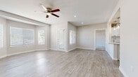 This single-story home offers a clean, modern interior finished with a neutral color palette throughout. The open living area is highlighted by light-toned wood-look flooring, recessed lighting, and a ceiling fan, creating a bright and airy atmosphere. Multiple windows dressed with white horizontal blinds invite abundant natural light, enhancing the spacious feel of the main living space.

The kitchen is thoughtfully designed with white shaker-style cabinetry, white quartz countertops, and a full suite of stainless steel appliances, including a French door refrigerator, electric range, and microwave. A peninsula provides additional prep and dining space. Conveniently, a dedicated laundry area with a full-size washer and dryer is tucked adjacent to the kitchen.

The bedrooms feature plush carpeting, ceiling fans, and generous wall space. The primary bedroom includes a sliding glass door that opens to an outdoor patio, offering pleasant exterior views. The bathrooms are well-appointed with wood-look tile flooring, white vanities with quartz countertops, brushed nickel fixtures, and a shower-tub combination. Additional rooms with light wood-look flooring provide flexible living or office space, rounding out this move-in-ready home.